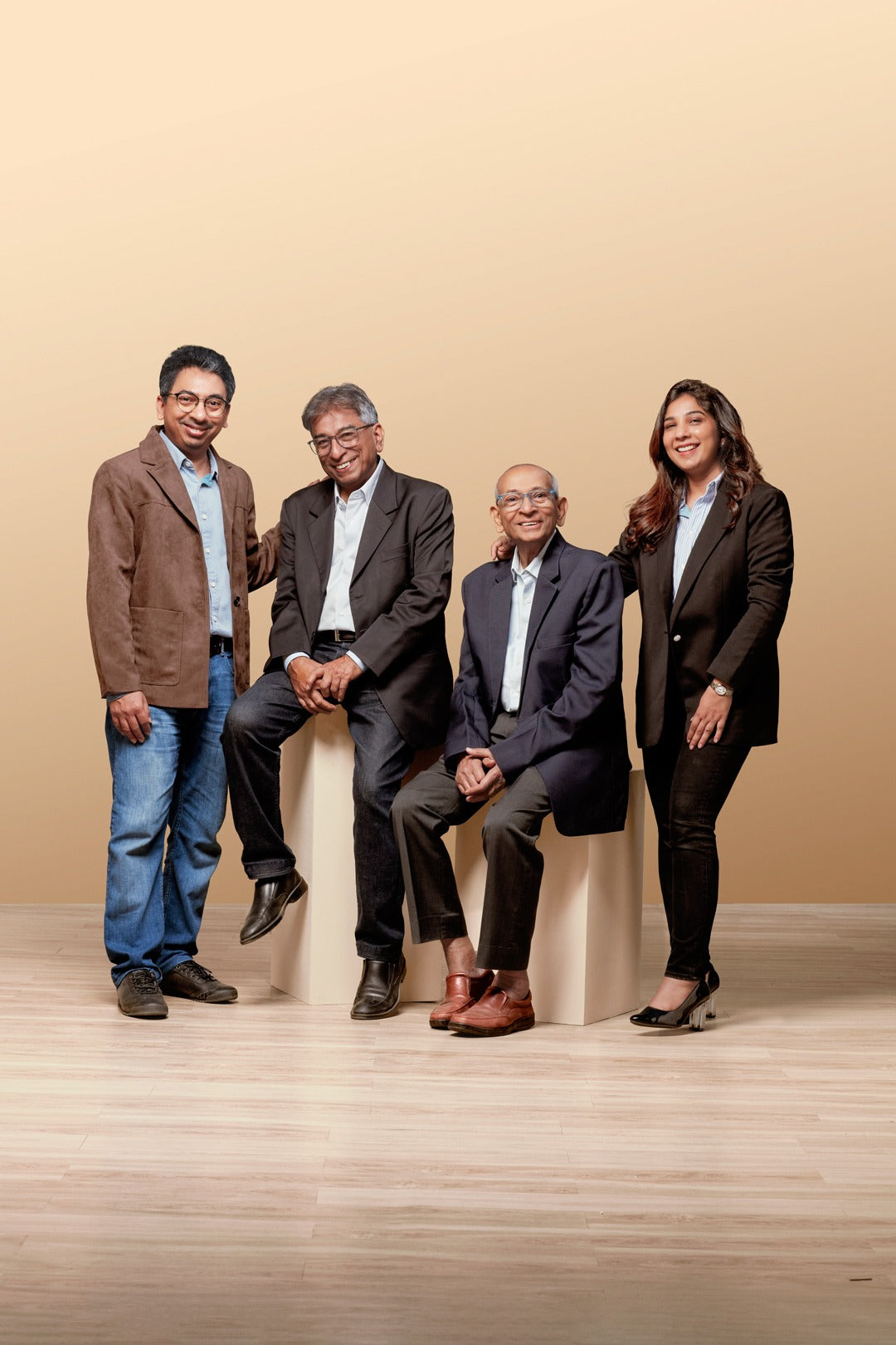 Four professionals in formal attire posing together against a beige background