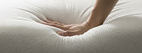 Hand touching a white mattress pad