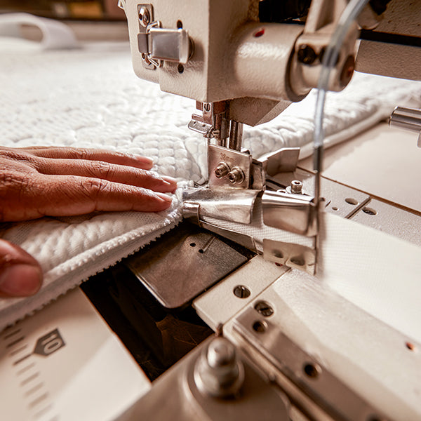 Close-up of a sewing machine in use with fabric and a hand guiding it.