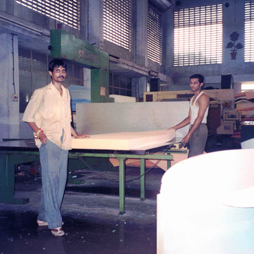 Two men working with large sheets of material in a factory setting