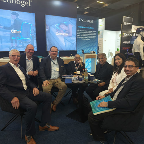 Group of people sitting together at an event with Technogel branding in the background.