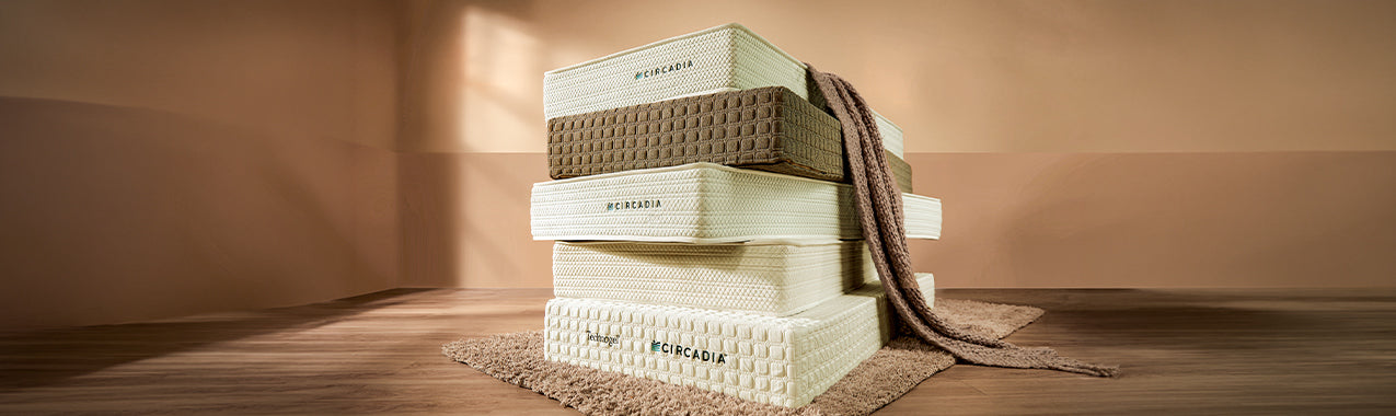 Stack of mattresses on a wooden floor with a neutral background