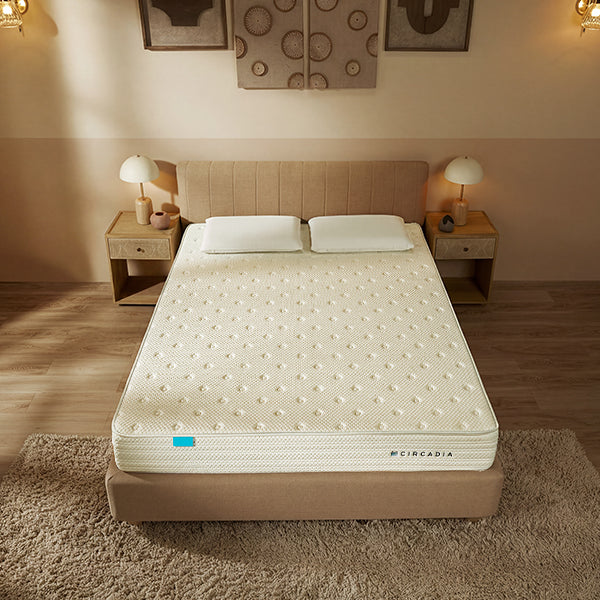 Beige mattress on a bed in a bedroom setting with bedside tables and lamps.
