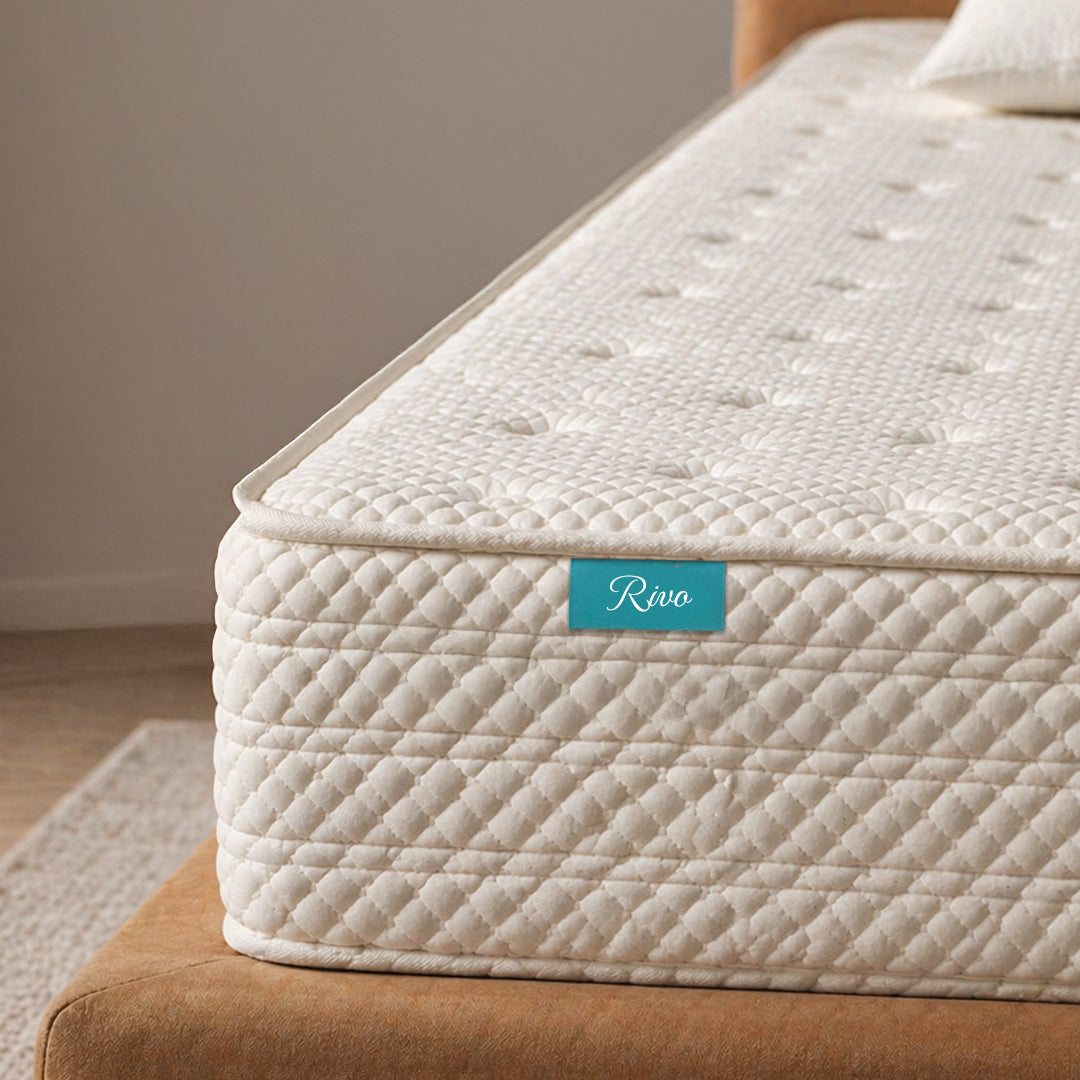 Beige mattress with 'Rivo' brand label on a brown couch.