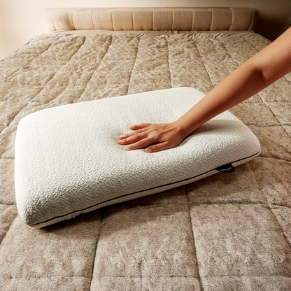Hand touching a white pillow on a beige bed