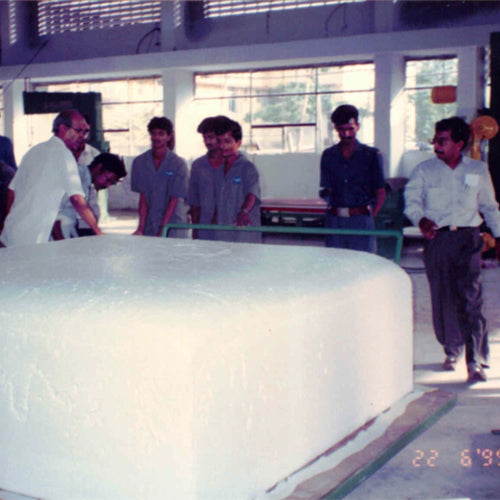 Group of people in a factory setting looking at a large white object.