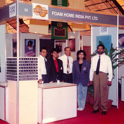 Group of people standing in front of a Foam Home India Pvt. Ltd. booth at an exhibition.