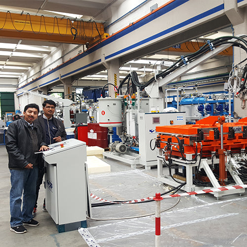 Two individuals standing next to a piece of industrial equipment in a factory setting.